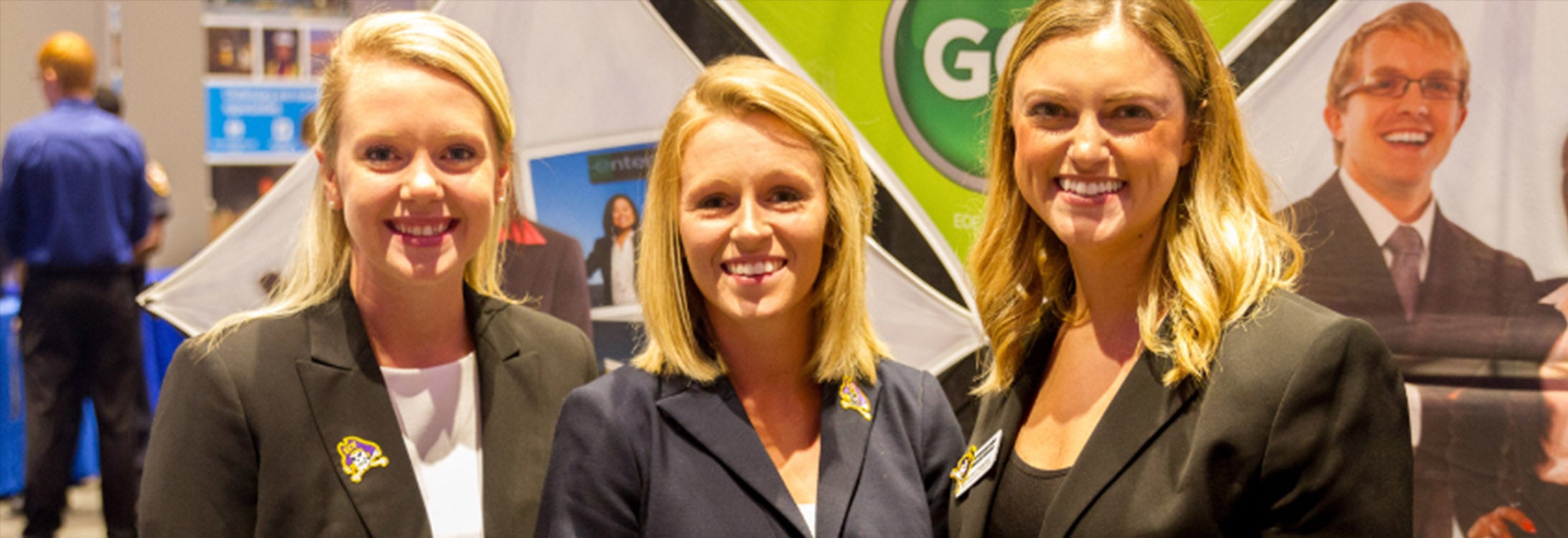 Employers at Career Fair smiling at camera outside of their booth.