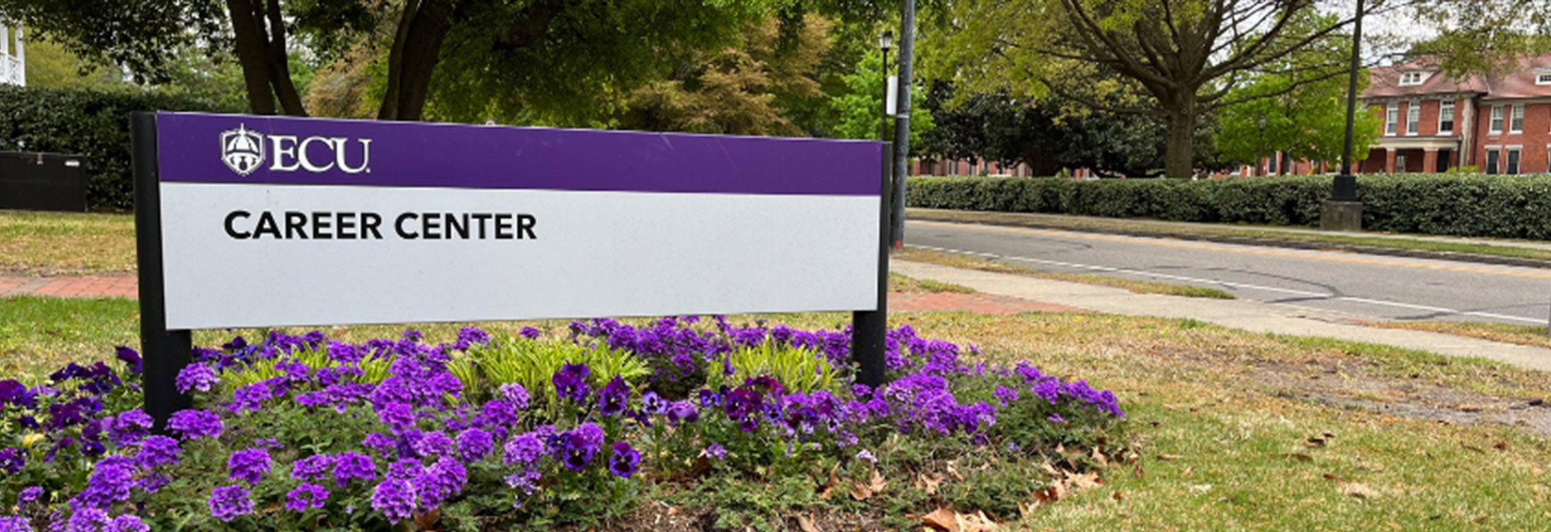 Career Center sign outside of house with purple flowers underneath.